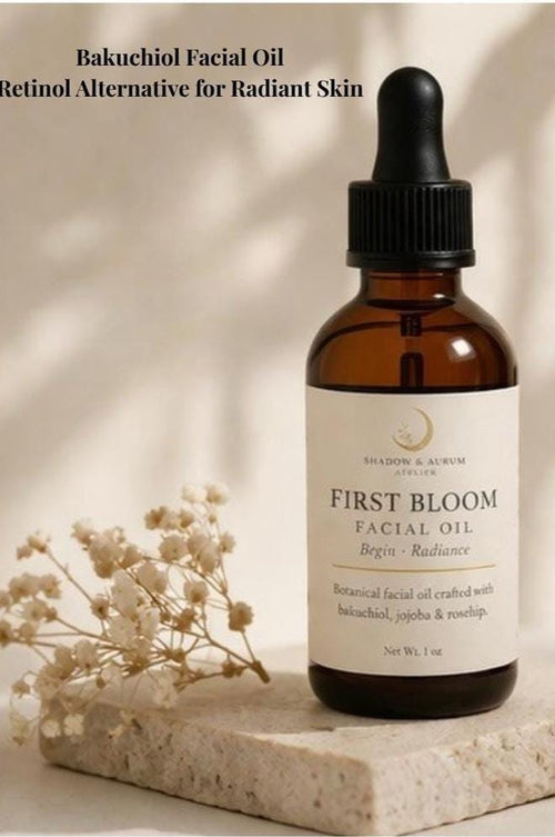 May include: A brown glass bottle of "First Bloom Facial Oil" with a black dropper, set on a stone surface. The label reads "Bakuchiol Facial Oil, Retinol Alternative for Radiant Skin." A sprig of white flowers is next to the bottle. Net Wt. 1 oz.